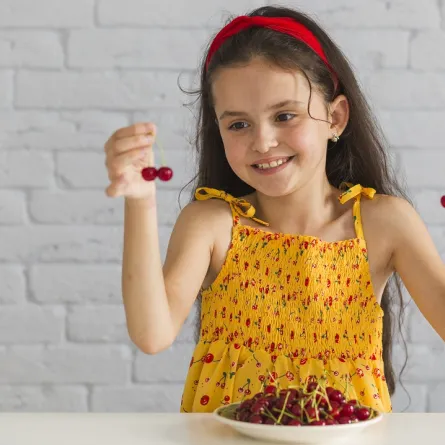 صورة لطفلة تحمل حبات من الكرز