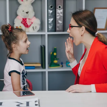 صورة لمدرسة تعلم الطفلة الكلام