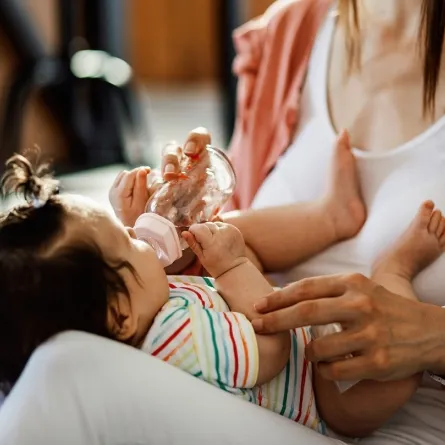 صورة لأم ترضع طفلتها الرضيعة من الزجاجة