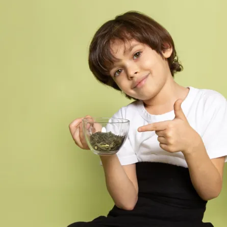 صورة طفل يشير إلى أوراق المورينجا المطحونة