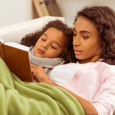 صورة لأم  تحكي لطفلتها قصة