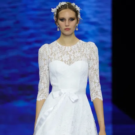 فستان أبيض من الغيبور ويتسم بحزام من الساتان الأبيض 