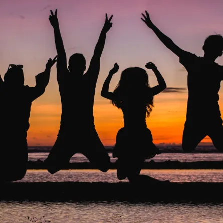 مجموعة من الأصدقاء يقفزون بالهواء الطلق عند الغروب