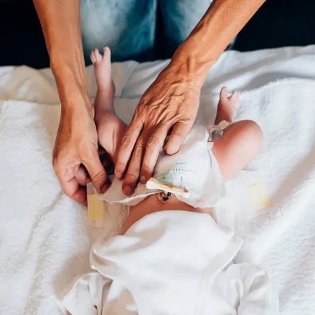 صورة لأم تغير حفاض طفلها الرضيع