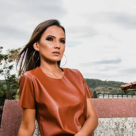 سيدة تبدو واثقة من نفسها تجلس على أريكة ومن ورائها الطبيعة الخلابة