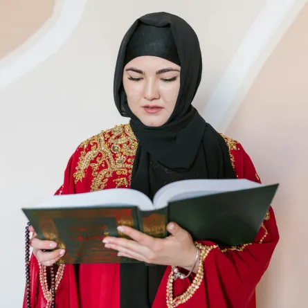 سيدة تمسك بمصحف شريف تتلو آيات من القرآن الكريم