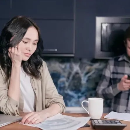 زوجة صامتة تجلس أمام جهازها اللوحي وزوج يبدو متشاغلاً بهاتفه المحمول