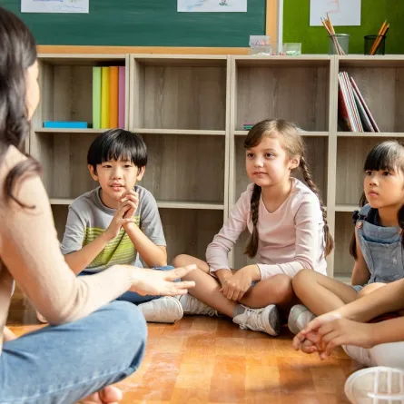 صورة لمعلمة تشرح والأطفال من حولها