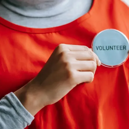 شابة تستعرض شارة التطوع من على ملابسها بفخر