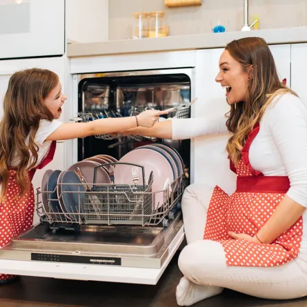 صورة لطفلة وأمها يرتبان حاجات الغسالة