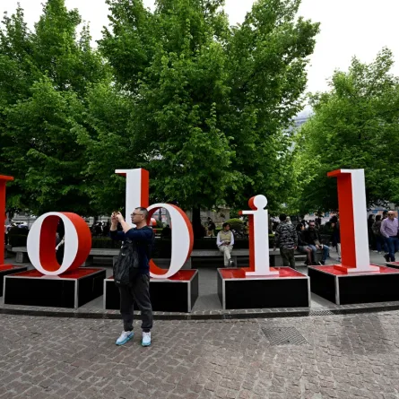 People stand next to a sign promoting the Salone del Mobile (furniture fair) on the eve of the Milan Design Week, on April 15, 2024 in Milan. (Photo by GABRIEL BOUYS / AFP)