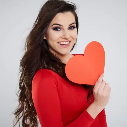 شابة جميلة تحمل قلباً من الورق