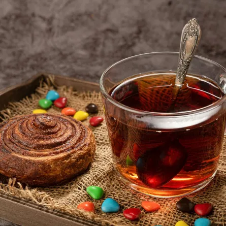 فنجان من الشاي اللذيذ وبجانبه مخبوزات وحلوى ملونة