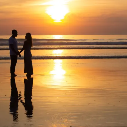 رجل وامرأة يمشيان على الشاطئ عند غروب الشمس