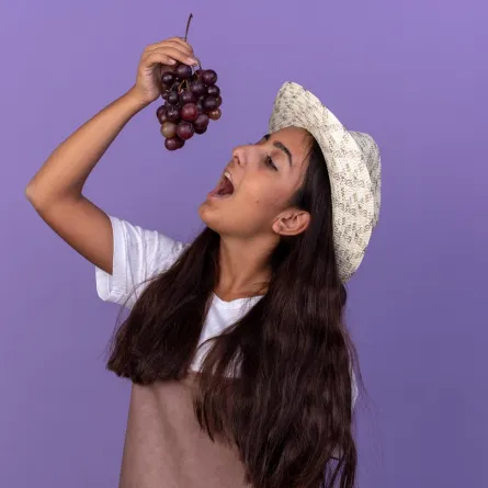 صورة لفتاة تمسك بعنقود للعنب