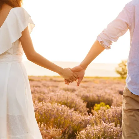 رجل وامرأة يمسكان أيديهما ويمشيان في الهواء الطلق