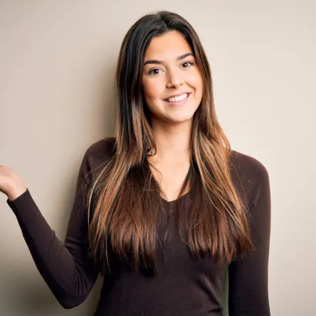 فتاة جميلة تبتسم بمرح وتشير براحة يدها وتنظر