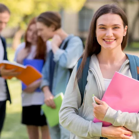 شابة تقف أمام مجموعة من الشباب من زملائها في الحرم الجامعي