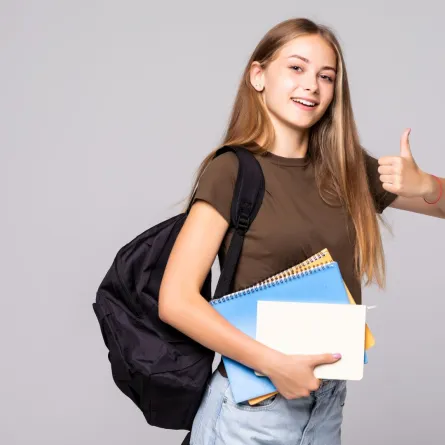 شابة تحمل حقيبتها وكتبها وتشير بعلامة النصر  