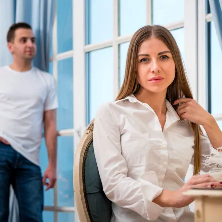 زوجة تبدو حزينة لتصرفات زوجها الذي يقف على الجانب الآخر