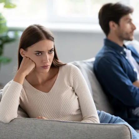 زوج وزوجته يجلسان على الأريكة ويتجاهلان بعضهما البعض