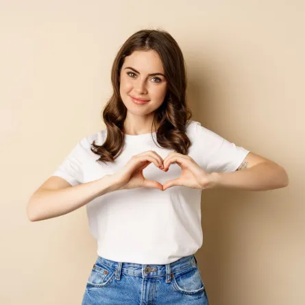 امرأة جميلة مبتسمة تُظهر علامة الحب