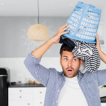 زوج فوضوي يمسك بسلة الملابس فوق رأسه