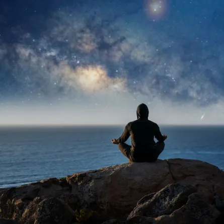 رجل يجلس على قمة الجبل ويتأمل في الليل 