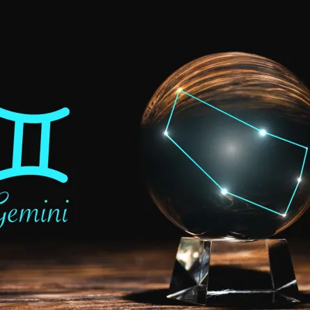 كرة بلورية بالقرب من علامة برج الجوزاء على طاولة خشبية