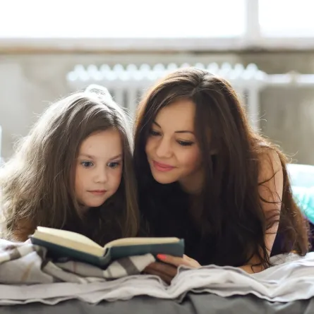 صورة لأم تحكي قصة لطفلتها