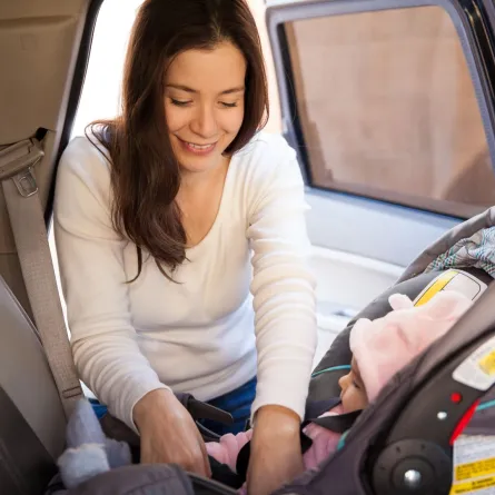 صورة لأم تضع طفلها في مقعد السيارة