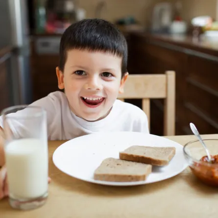 صورة لطفل يحصل على كوب من الحليب قبل المدرسة