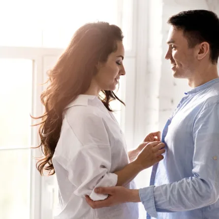 زوجة محبة لزوجها تضع يديها على صدره وهو يمسك بمرفقيها بحنان