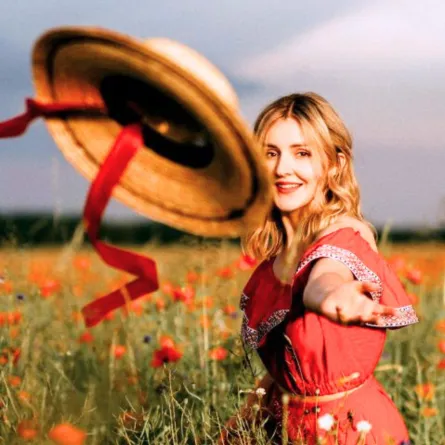 فتاة تلقي بقبعتها ببهجة ومرح وسط حقول الزهور