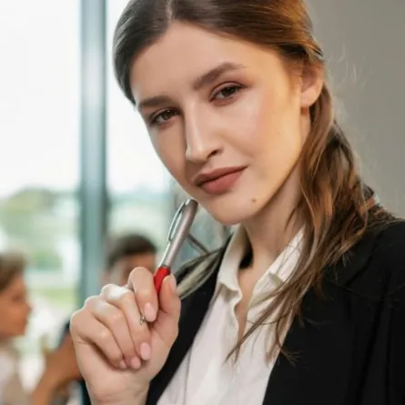  شابة تبدو ذات استقلال شخصي تنظر بثقة وتُشير بقلمها باعتداد