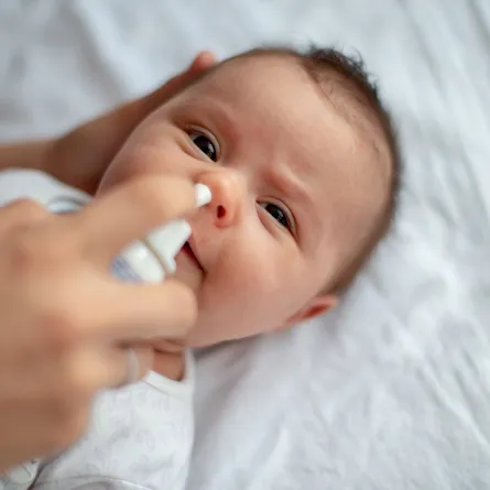 صوة لأم تضع قطرة الملح بأنف الطفل