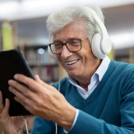 أحد كبار السن يبدو سعيداً باستخدامه جهاز التابلت الخاص به 