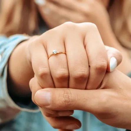 خطيب يمسك يد خطيبته وهي تستعرض خاتم خطوبتهما بسعادة