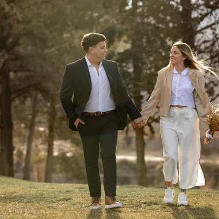 زوج يمسك بيد زوجته وهي تمسك باقة من الزهور وتبتسم به بسعادة 