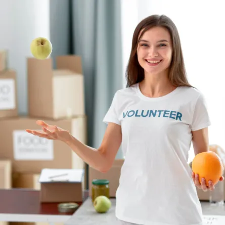 شابة متطوعة تمسك بيدها بعض ثمار الفاكهة لإرسالها للمحتاجين