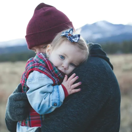 طفلة رضيعة تضع رأسها على كتف والدها بسلام ومحبة واطمئنان