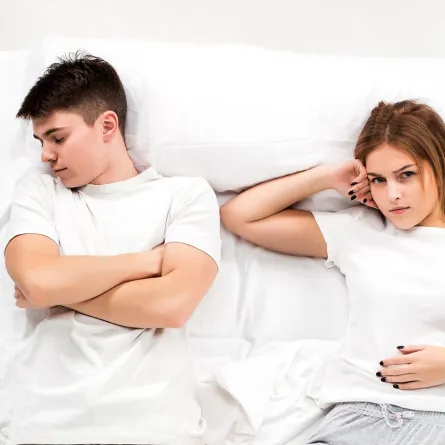 زوجان مستلقيان على سريرهما ويبدو الزوج محاولا الاختباء من كذبه والزوجه كشفته