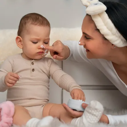 صورة لأم تقوم بترطيب بشرة طفلها