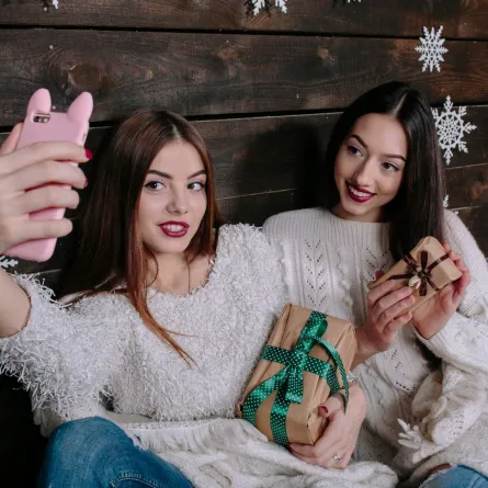 صديقتان كل تحمل هدية للعام الجديد وتلتقطان سيلفي 