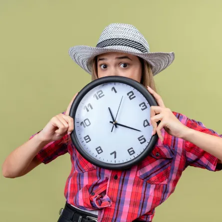   شابة تمسك بيدها ساعة كبيرة وتبدو خائفة من ضياع وقتها   