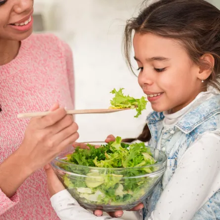 صورة لأم تقدم الخس لطفلتها مع طبق السلطة