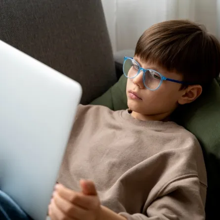 صورة لطفل مندمج مع جهازه الاليكتروني