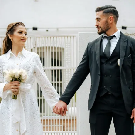 خطيبان يمسك كل خطيب بيد الآخر بسعادة والخطيبة تمسك بيدها باقة من الزهور