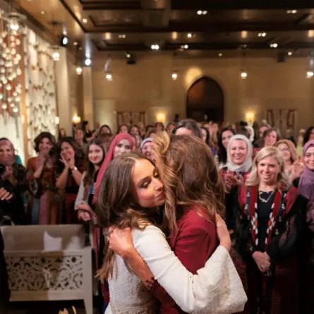 الملكة رانيا تعانق ابنتها الأميرة إيمان بنت عبدالله خلال حفل ليلة الحناء (Queen Rania hugging her daughter Princess Iman bint Abdullah during a henna night ceremony). مصدر الصورة: Office of Her Majesty Queen Rania Al Abdullah / AFP
