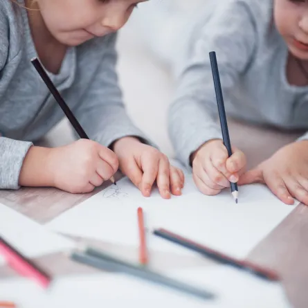 صورة لطفلين يمسكان بالقلم